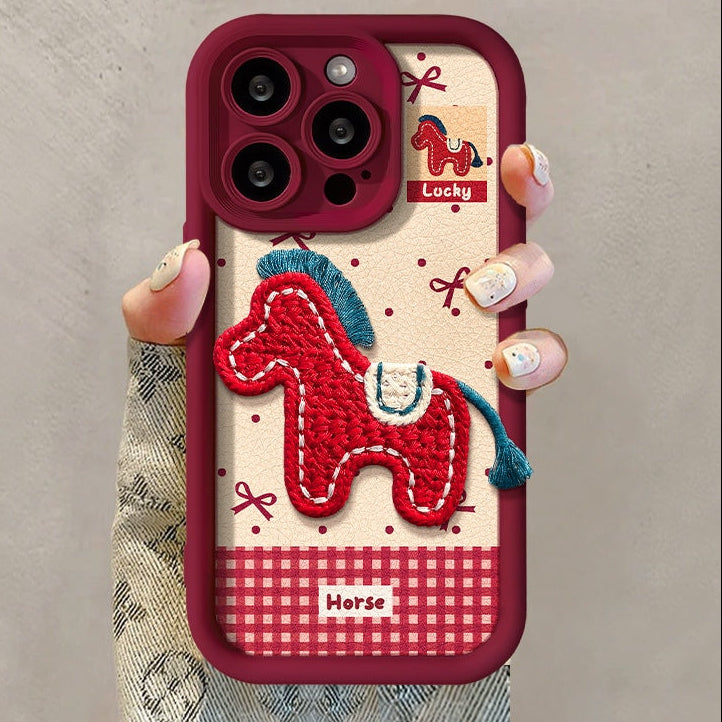 Phone case with embroidered horse design held by a hand