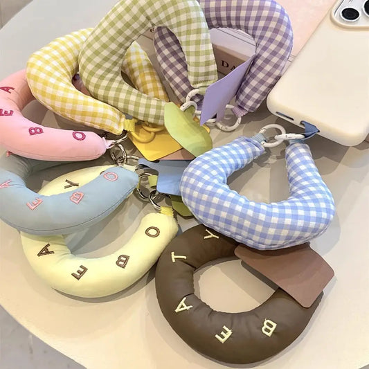 Colorful neck pillow keychains with checkered patterns on a light surface.