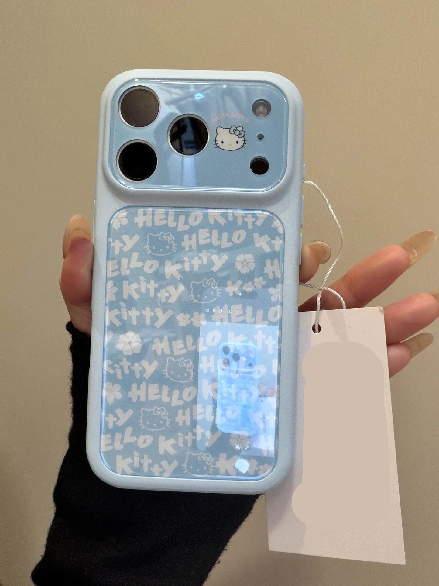 Phone case with 'Hello Kitty' design held by a person, with a tag displaying 'INS HOUSE'.