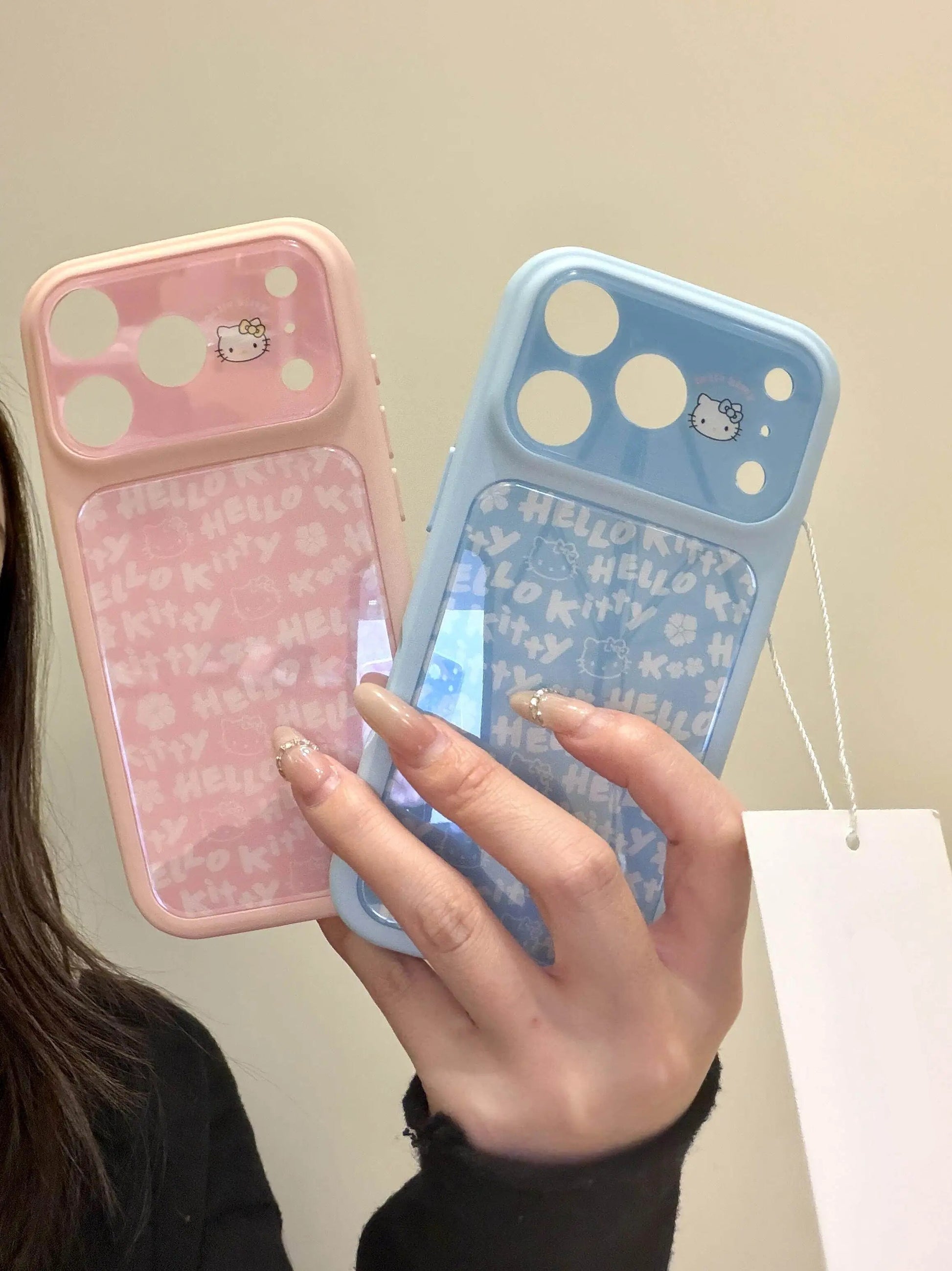 Two phone cases, one pink and one blue, held by a person with a beige background.