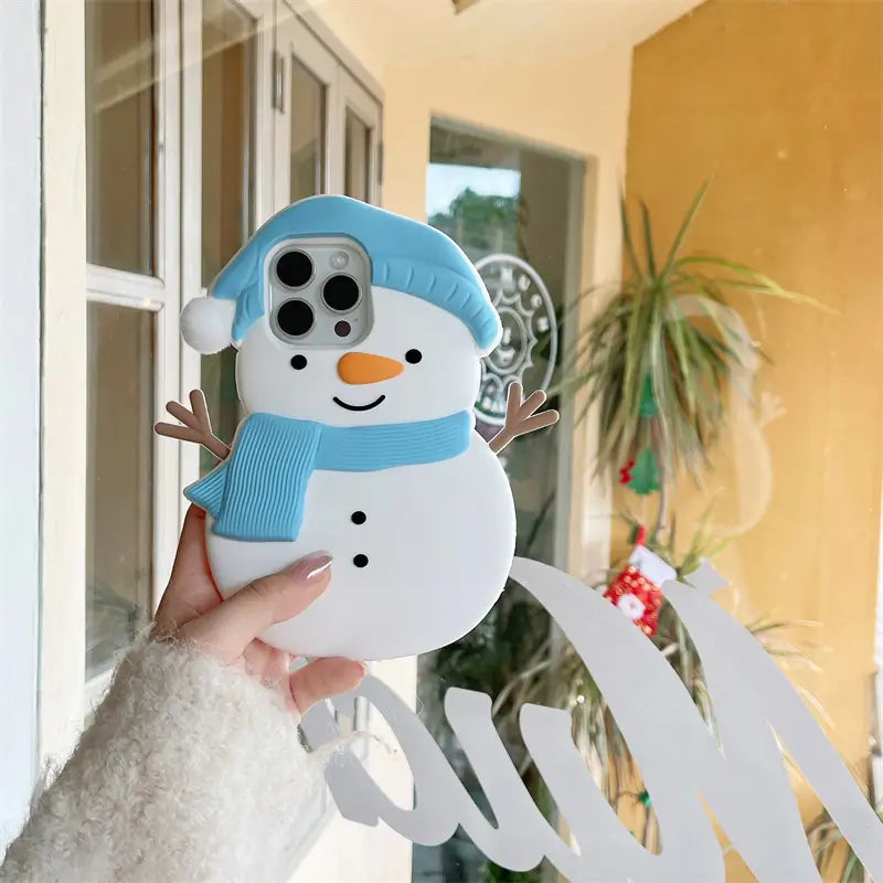 Snowman-shaped phone case held by a hand with a blurred indoor background